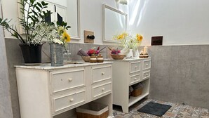 A bathroom with a white vanity, two sinks, a mirror, and a patterned tile floor.