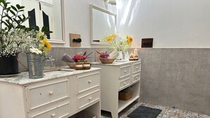 A bathroom with a white vanity, a mirror, and a tiled floor.