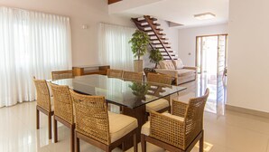 Ein modernes Wohnzimmer mit Glastisch, Korbstühle, einer Couch, einer Treppe und einer Topfpflanze.