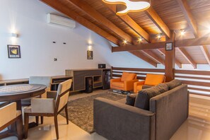 A modern loft-style living area with a fireplace, seating, and a dining table. - Casa com 3 Suítes, Piscina e Churrasqueira (Guarujá)