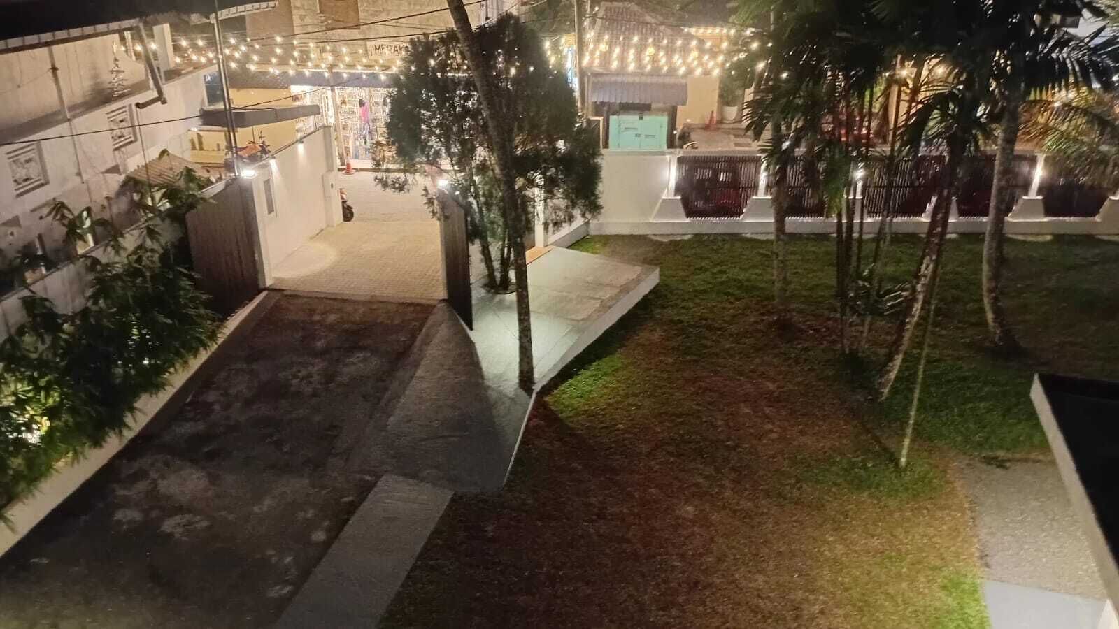 A courtyard with a paved area, palm trees, and string lights.