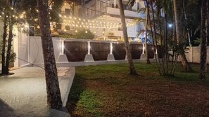A nighttime outdoor area with string lights, trees, and a white fence. - Golden Ente (Unawatuna)