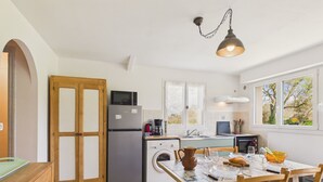 Une cuisine équipée d’un réfrigérateur, d’un four à micro-ondes, d’un lave-linge et d’une table à manger avec des chaises.