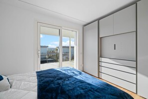 Una camera da letto con un letto, un armadio e una porta scorrevole in vetro che dà su un balcone.