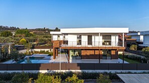 Una moderna casa a due piani con un balcone, una piscina e un giardino curato.
