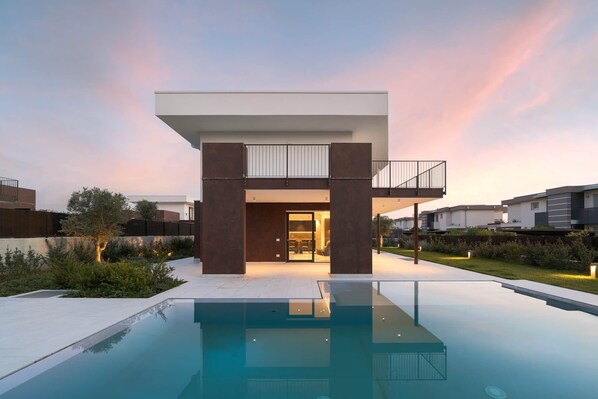 Ein modernes Haus mit Pool, Balkon und einem gepflegten Garten.