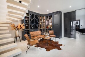 A modern living room with a leather sofa set, a coffee table, and a large wine rack.