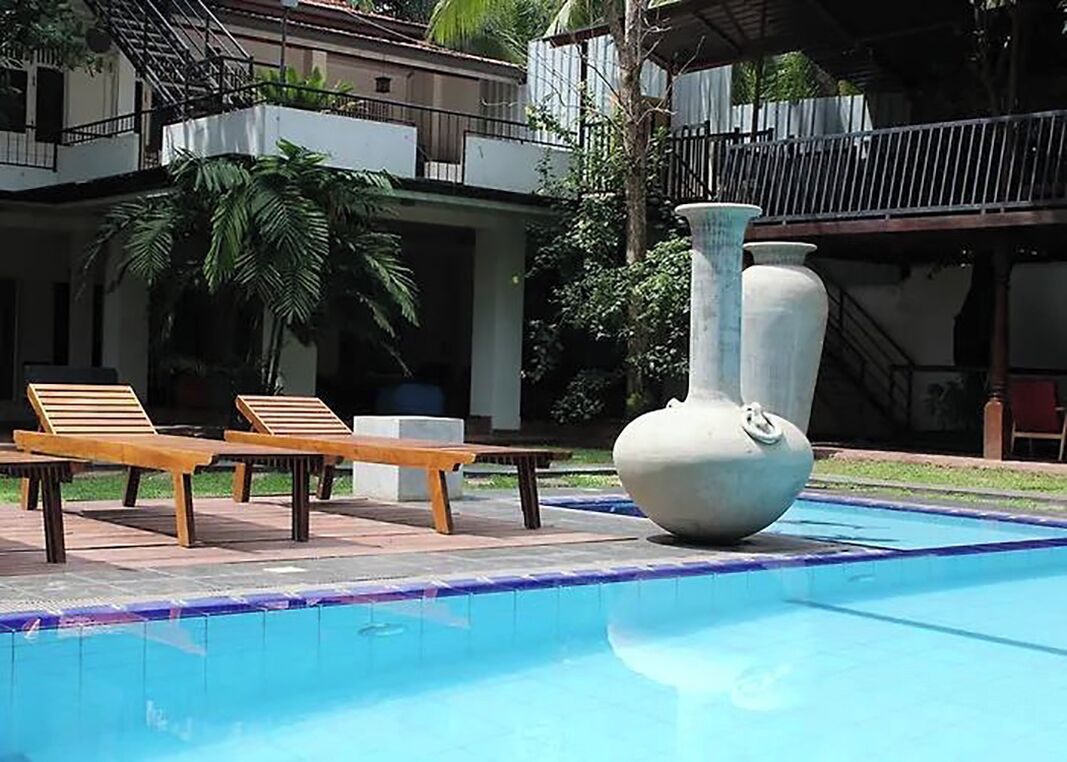 A swimming pool with lounge chairs and a large vase.