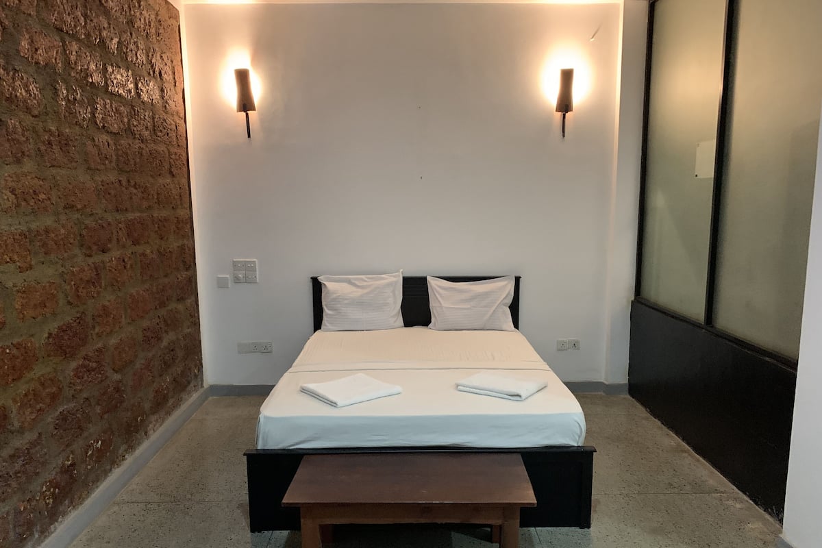 A neatly arranged bedroom with a bed, bedside tables, and two wall-mounted lights.