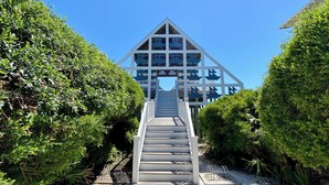 Una escalera que lleva a un edificio con techo triangular y múltiples ventanas.