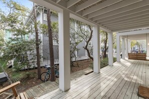 A covered porch with wooden flooring, white columns, and trees. - 2 BD In Heart of Seaside, Perfect for Young Families, Walk to Beach & Town (Santa Rosa Beach)