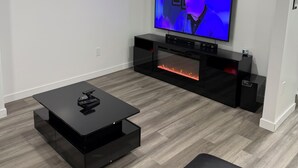 Una sala de estar moderna con televisor de pantalla plana, mueble de entretenimiento negro y una chimenea.
