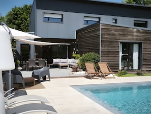 A modern house with a swimming pool, outdoor furniture, and a patio area. - Guest Room 'L'Abri des Flots' with Shared Pool, Terrace, and Wi-Fi (Plouër-sur-Rance)