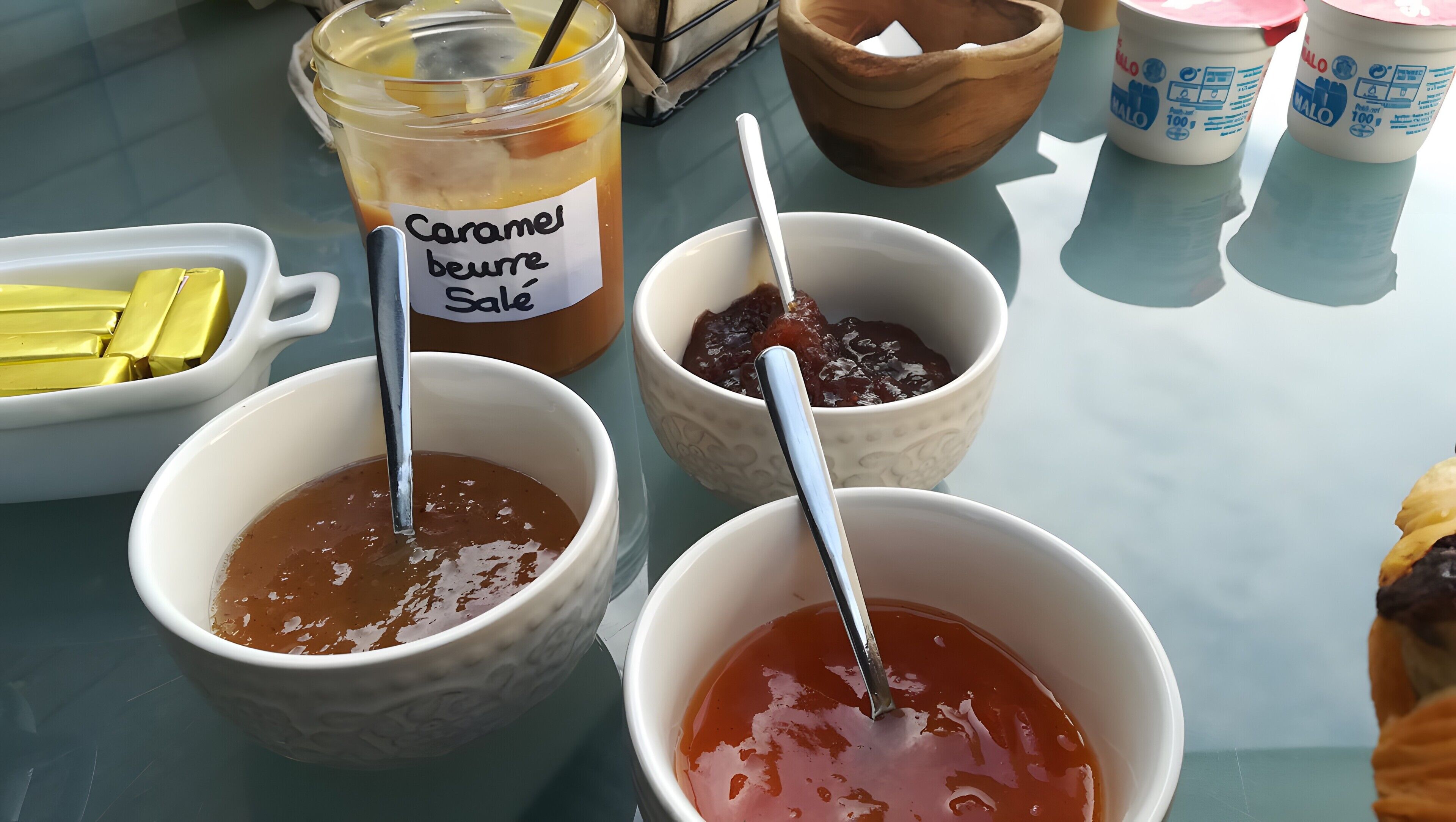 Et bord med forskelligt mad, herunder skåle med karamelsauce og et glas med teksten 'Caramel beurre Sale'.