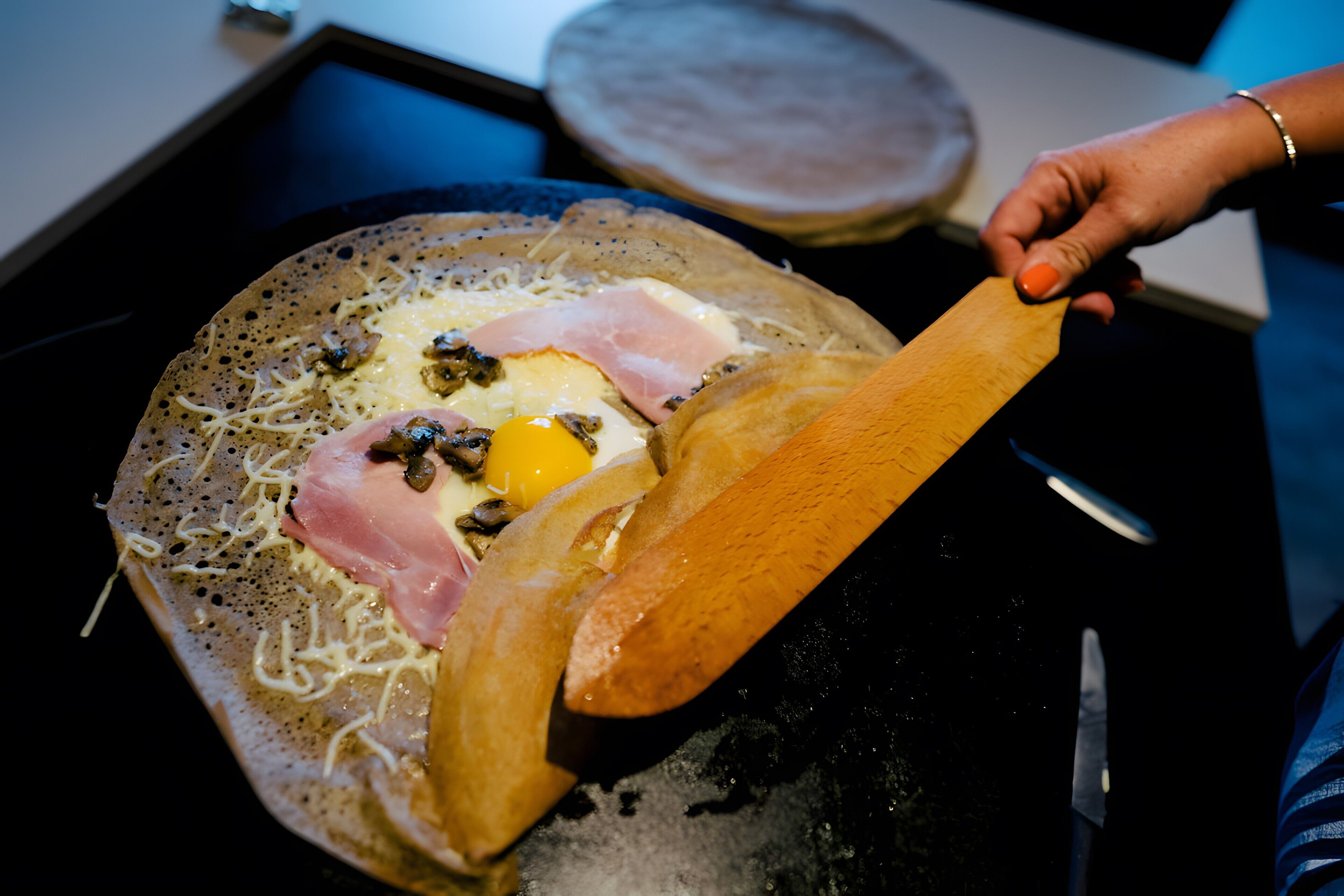 A person cooking an omelette on a flat griddle.
