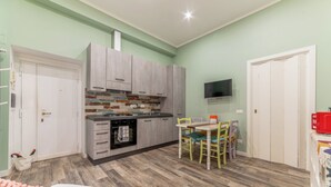 Une cuisine compacte avec un coin repas, un téléviseur fixé au mur et un lit en premier plan.