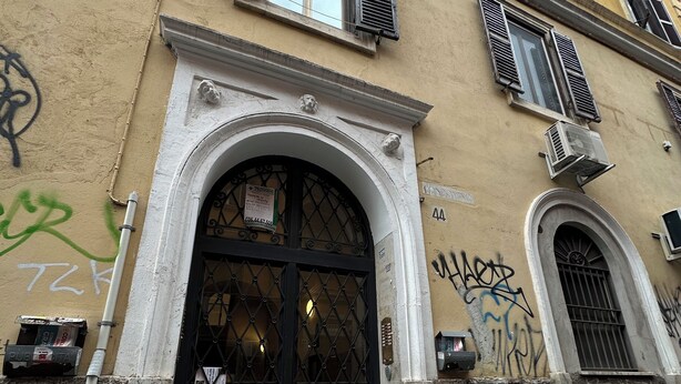 Un bâtiment doté d’une entrée arquée noire, de nombreuses fenêtres avec volets et d’une sonnette bien visible.