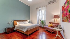 Une chambre à coucher comprenant un lit, une table de chevet, une lampe et une petite table avec une bouilloire.
