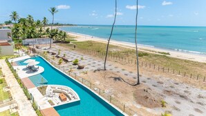 Un complexe hôtelier doté d’une piscine, d’une plage et de palmiers.