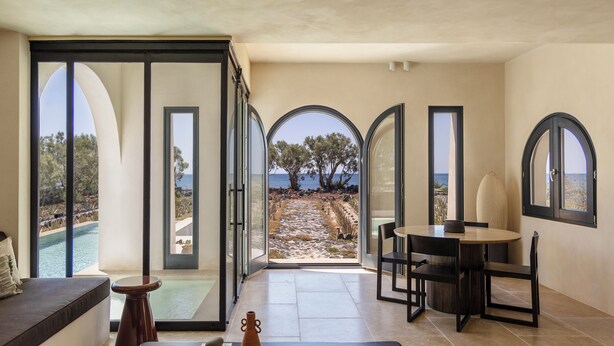 A modern interior with a view of the sea, a dining area, and a seating space. - Exomitis1 Cellar & Sea Escape (Santorini)