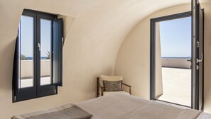 A bedroom with a bed, a chair, and a large window with a view. - Exomitis1 Cellar & Sea Escape (Santorini)