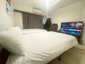 A hotel room with a large bed, a television, an air conditioning unit, and a cabinet. - shibuya station 5min room (Tokyo)