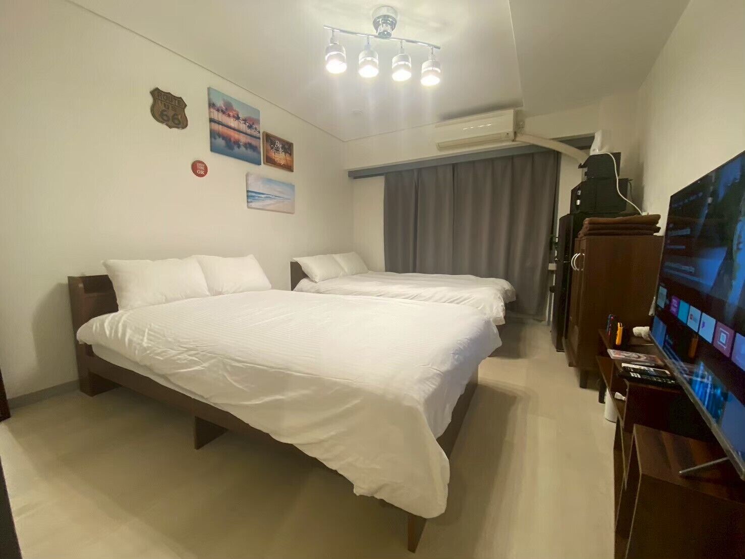 Ein Hotelzimmer mit zwei Betten, einem Fernseher und einer Deckenleuchte.