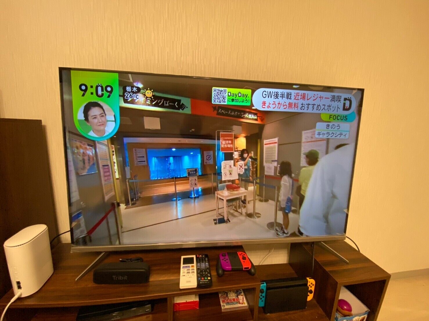 Un televisor mostrando imágenes de videovigilancia de un vestíbulo con mostrador de recepción, señalización y algunas personas.
