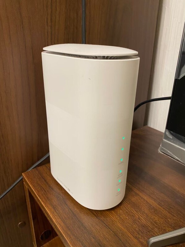 A white cylindrical device on a wooden table, with a cable connected to it. - shibuya station 5min room (Tokyo)