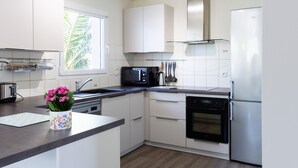 Een moderne keuken met witte kasten, een roestvrijstalen koelkast, een magnetron en een vaatwasser.