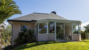Een huis met een overdekte patio, een schuin dak en een verzorgd gazon.
