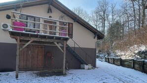 Een gebouw met een houten trap die naar een balkon leidt, een deur en een met sneeuw bedekte grond.