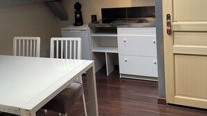 Een compacte keuken met dakraam, witte kastjes, een eettafel met stoelen en een houten vloer.