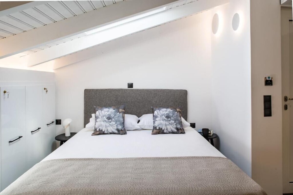 Ein Schlafzimmer mit einem Bett, zwei Nachttischen, einer weißen Tür und einer Deckenleuchte.