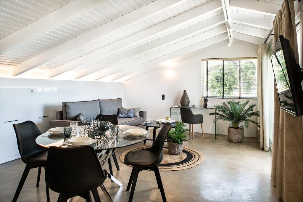 A modern loft with a dining area, a sofa, and a large window.