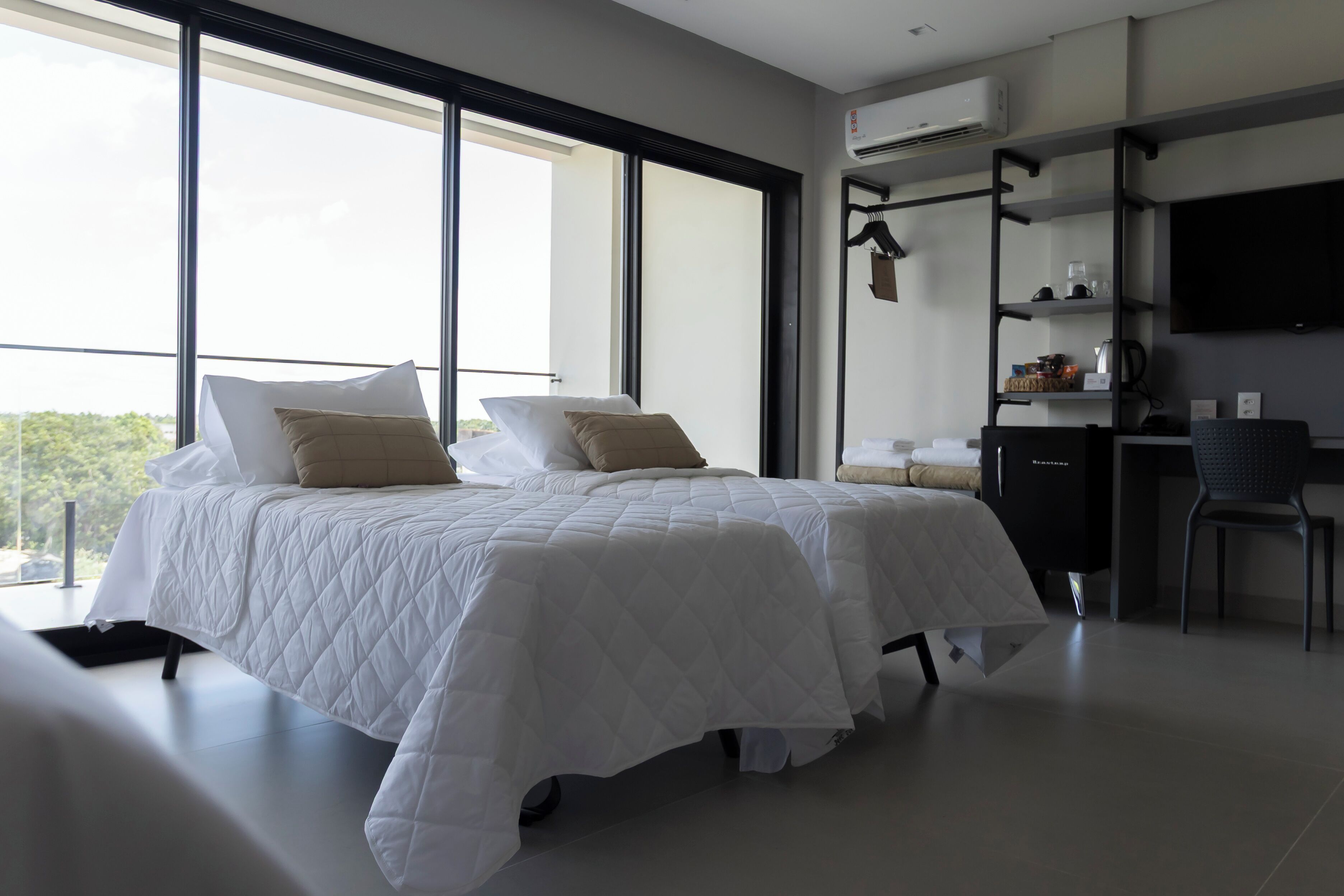 A modern hotel room with a large bed, a desk, and a TV.