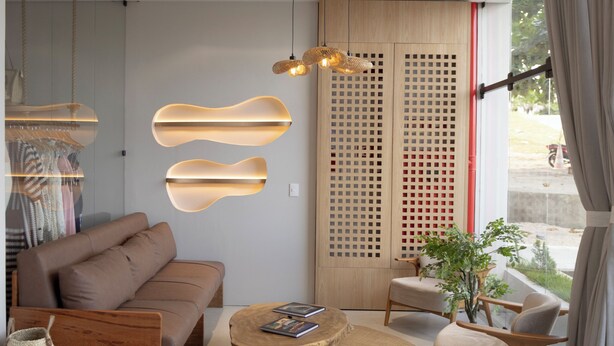 A modern living room with a sofa, coffee table, and chairs, a large window with curtains, and a decorative wall panel. - Duna Queen Hotel Conceito (Barreirinhas)