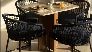 A dining area with a table set for two, surrounded by four black chairs with a woven seat design. - Duna Queen Hotel Conceito (Barreirinhas)