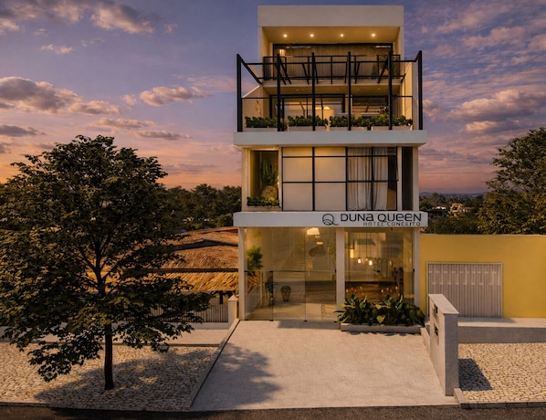 A modern hotel with a two-story structure, a visible entrance, and a sign indicating the name 'DUNa Queen Hotel Conceito.'