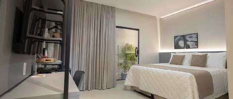 A modern hotel room with a bed, a desk, a chair, a potted plant, and a window with curtains.