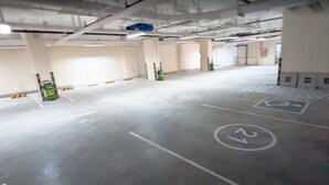 Pysäköintihalli, jossa on selkeät kaistamerkinnät, palosammutin ja sininen hätäuloskäynti.