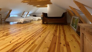 A room with wooden beams, a bed, a bench, and a framed picture on the floor. - Maison 'Lilas Rose' 300m², 12 guests, private garden and barbecue (Le Mas-de-Tence)