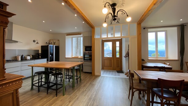 A spacious kitchen with wooden beams, a dining area with a large table, and a view through the window. - Maison 'Lilas Rose' 300m², 12 guests, private garden and barbecue (Le Mas-de-Tence)