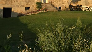 A stone building with multiple windows, a chimney, and a small garden area with outdoor furniture. - Maison 'Lilas Rose' 300m², 12 guests, private garden and barbecue (Le Mas-de-Tence)