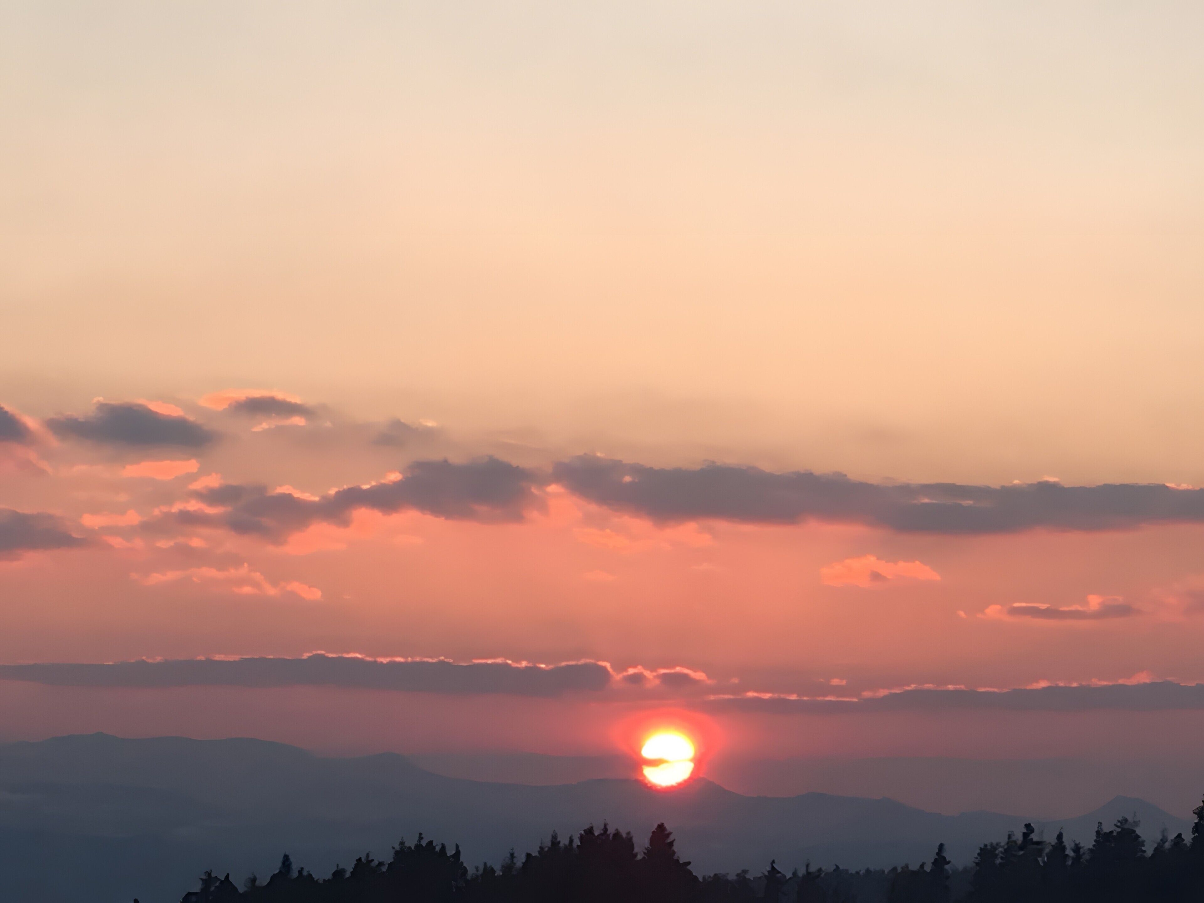 Een zonsondergang boven een bergketen met wolken.