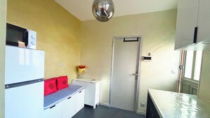 Eine kleine Küche mit Kühlschrank, Spüle und einer Tür zu einem weiteren Raum.
