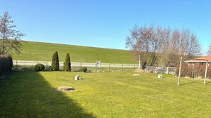 Um campo gramado com cerca, árvores e um coreto.