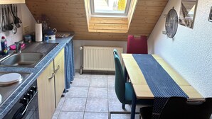 Uma cozinha compacta com claraboia, uma mesa de jantar e um radiador.