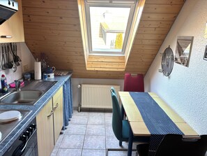 Eine kompakte Küche mit Oberlicht, Esstisch und Heizkörper.