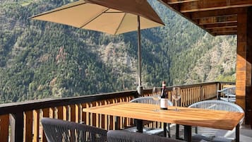 Eine Holzterrasse mit Tisch und Stühlen mit Blick auf eine Berglandschaft.
